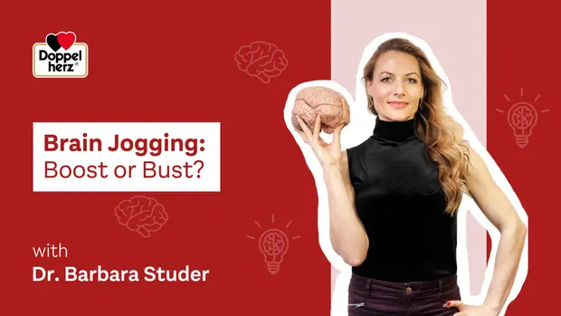 Ženska drži model človeškega možgana in se nahaja na rdečem ozadju s simboli svetlobe. V zgornjem delu je napis "Brain Jogging: Boost or Bust?" in navedeno je ime "Dr. Barbara Studer.